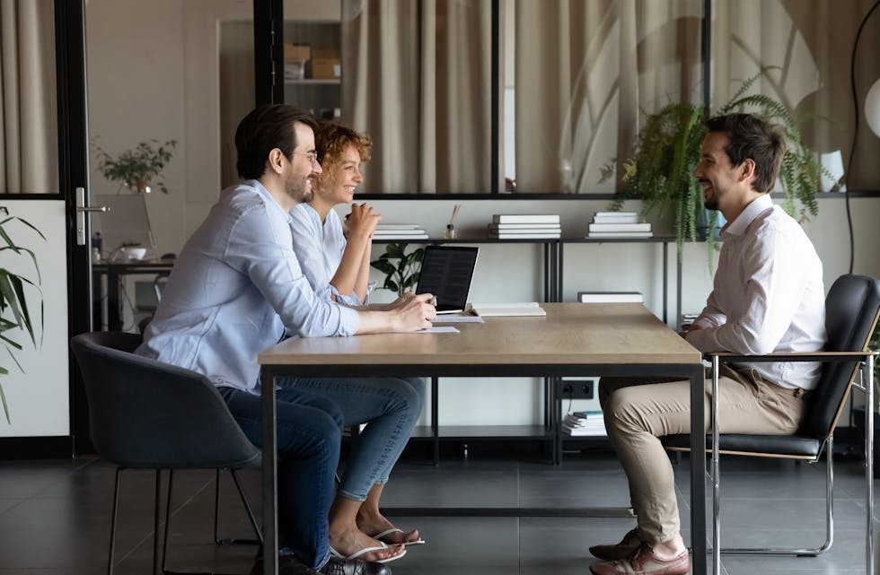 Happy recruiters talk with male applicant in office