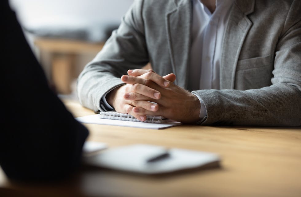 Two businessmen with clasped hands sitting opposite close up