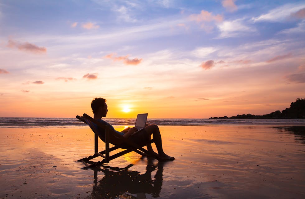 business man with laptop working on the beach