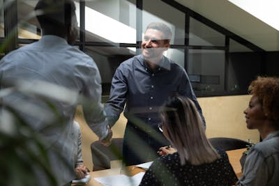 African American leader shaking hand of smiling employee at meeting