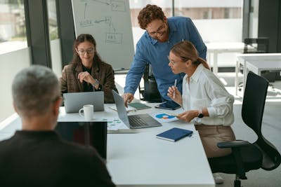 Group of young business people discussing something and smiling while sitting at the office table